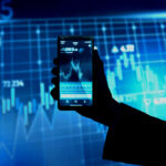 Hånd som holder oppe en telefon og trader på Bitcoin